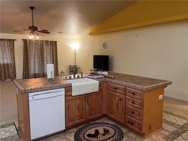 kitchen with tile countertops, white dishwasher, a sink, visible vents, and vaulted ceiling