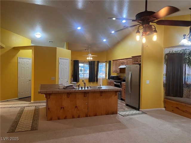 kitchen featuring tile counters, appliances with stainless steel finishes, a sink, ceiling fan, and under cabinet range hood