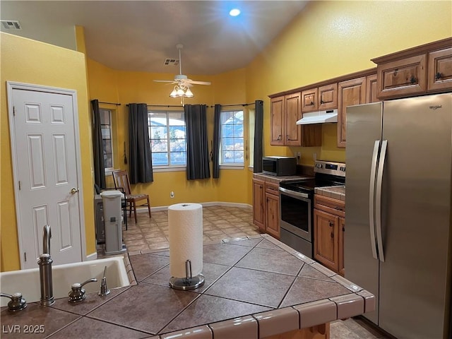 kitchen with stainless steel appliances, visible vents, under cabinet range hood, and tile countertops