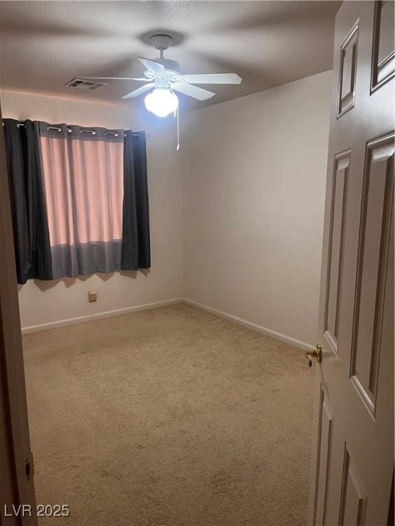 spare room with carpet floors, baseboards, visible vents, and a ceiling fan