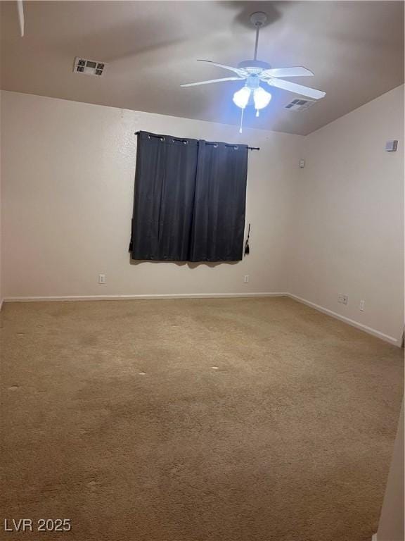 carpeted empty room with a ceiling fan, visible vents, vaulted ceiling, and baseboards