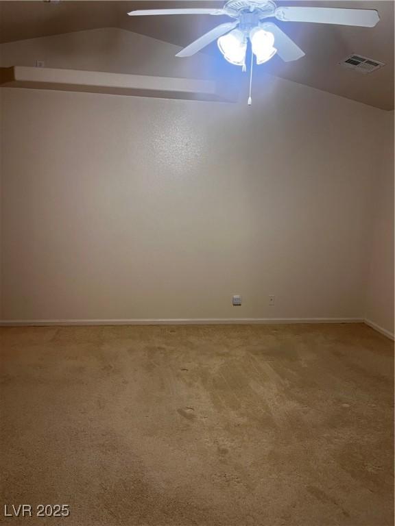 empty room with lofted ceiling, light colored carpet, visible vents, ceiling fan, and baseboards