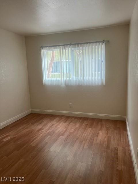 empty room with baseboards and wood finished floors