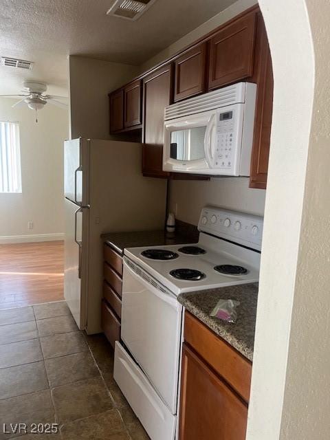 kitchen featuring ceiling fan, white appliances, a textured ceiling, and visible vents