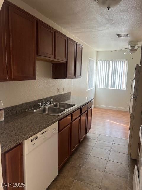 kitchen featuring white appliances, visible vents, a ceiling fan, a textured ceiling, and a sink