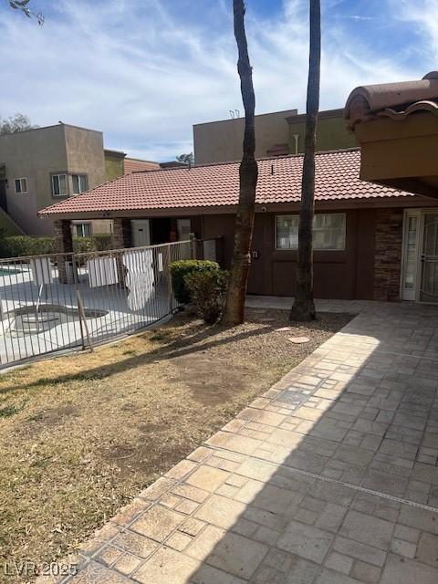 back of property featuring a tiled roof, fence, and stucco siding