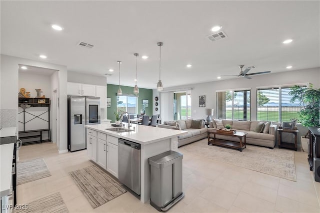 kitchen featuring visible vents, white cabinets, appliances with stainless steel finishes, open floor plan, and a sink