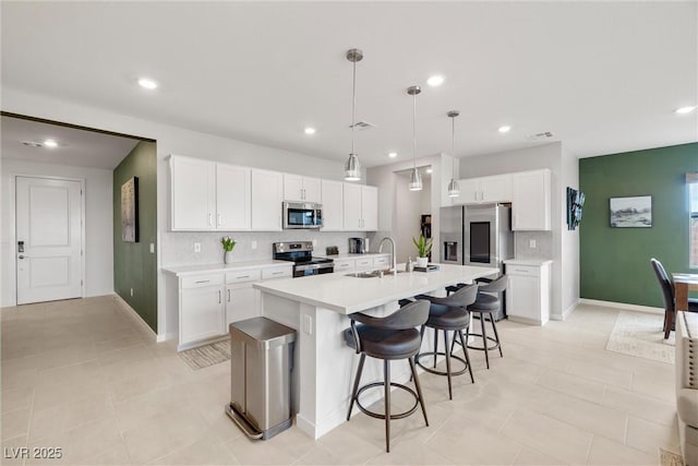 kitchen with a center island with sink, a breakfast bar area, stainless steel appliances, light countertops, and a sink