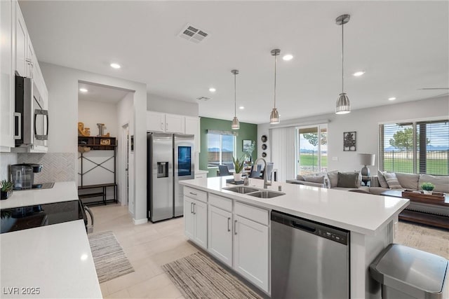 kitchen with light countertops, visible vents, appliances with stainless steel finishes, white cabinets, and a sink