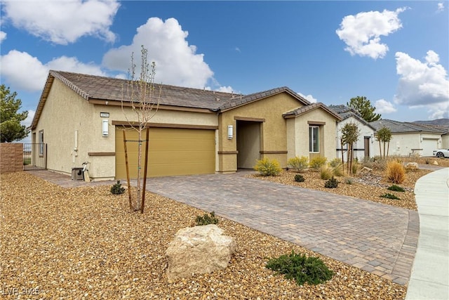 view of front of property featuring decorative driveway, a tile roof, stucco siding, an attached garage, and fence