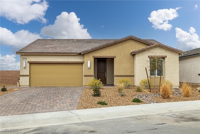 ranch-style home featuring a garage, decorative driveway, a tiled roof, and stucco siding