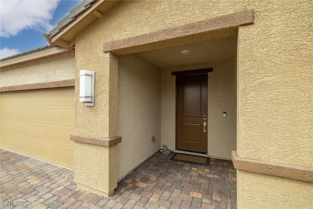 property entrance with a garage and stucco siding