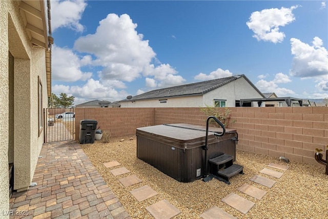 view of patio with a fenced backyard, a gate, and a hot tub