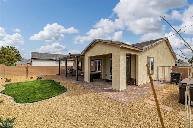 back of house featuring a gate, a patio area, a fenced backyard, and stucco siding