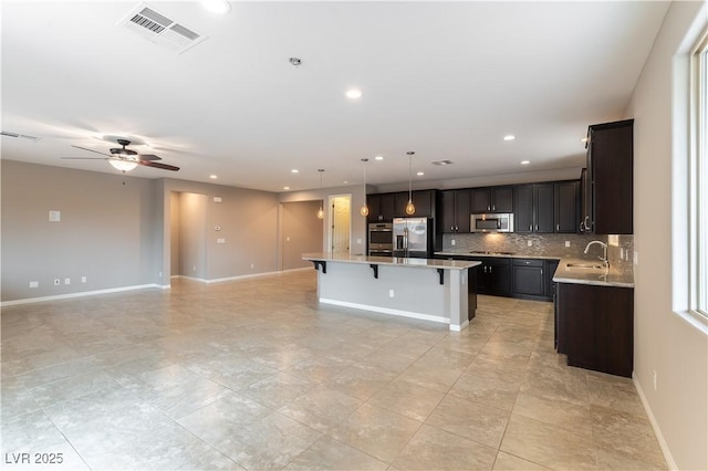 kitchen with visible vents, appliances with stainless steel finishes, open floor plan, a center island, and a sink