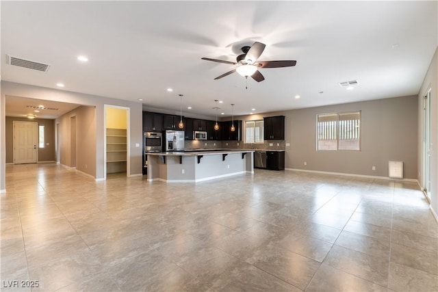 unfurnished living room with a ceiling fan, recessed lighting, visible vents, and baseboards