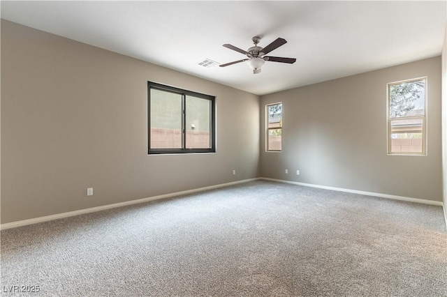 empty room with carpet floors, visible vents, baseboards, and a ceiling fan