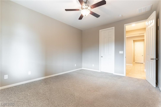 unfurnished bedroom featuring a ceiling fan, light colored carpet, visible vents, and baseboards