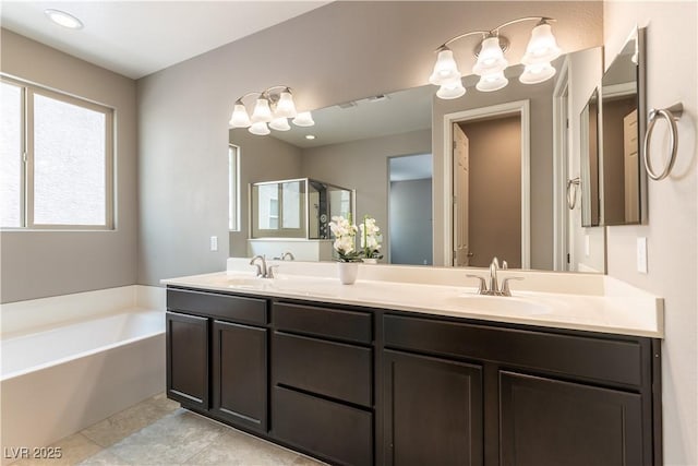 full bath featuring a garden tub, double vanity, a sink, and tile patterned floors