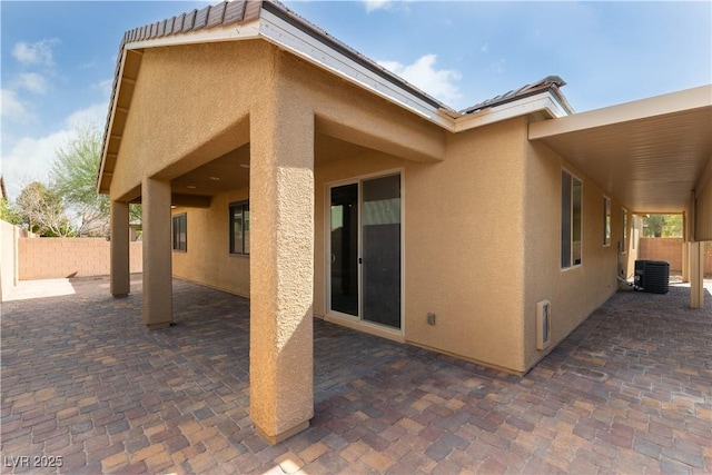 exterior space featuring a patio area, fence, and stucco siding