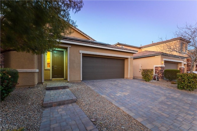 view of front of home with a garage, decorative driveway, and stucco siding