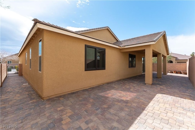 view of property exterior featuring a patio area, fence, and stucco siding