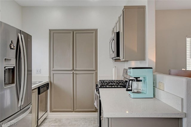 kitchen with light stone countertops, stainless steel appliances, and gray cabinetry