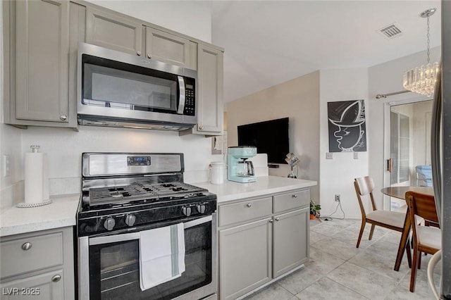 kitchen with a chandelier, light countertops, appliances with stainless steel finishes, and gray cabinetry