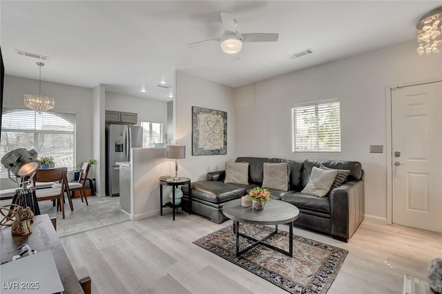 living area with light wood-style floors, visible vents, and a wealth of natural light