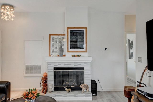 living area with a fireplace, baseboards, and wood finished floors