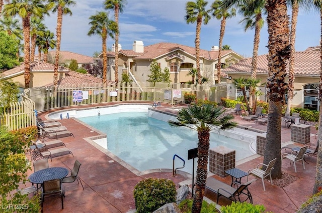 community pool with a patio and fence