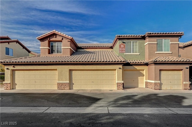 mediterranean / spanish-style house featuring stone siding, a tiled roof, and stucco siding