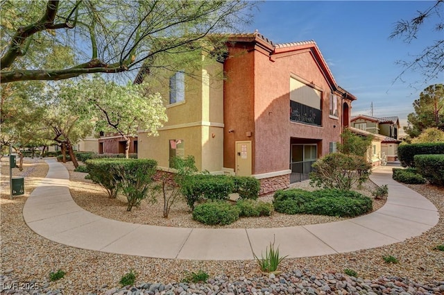 view of side of property featuring a tile roof and stucco siding