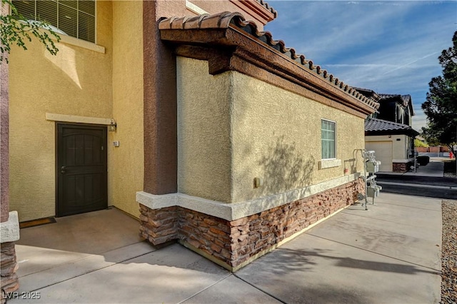 view of property exterior with stone siding, a tile roof, and stucco siding