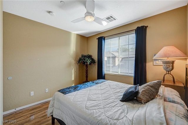 bedroom featuring visible vents, ceiling fan, baseboards, and wood finished floors