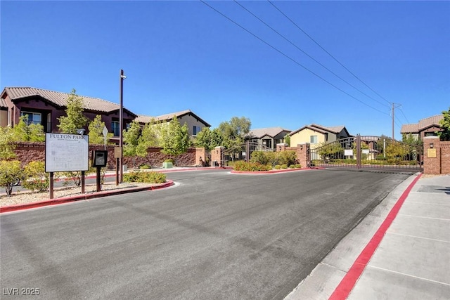 view of street with a gate, sidewalks, a gated entry, a residential view, and curbs