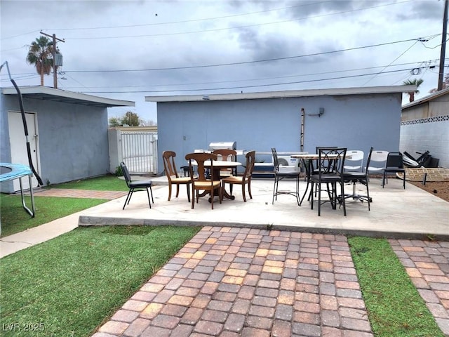 view of patio / terrace with a trampoline, outdoor dining area, and an outdoor structure