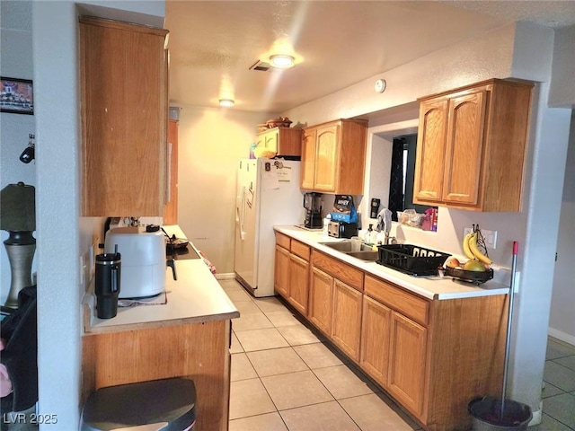 kitchen with light tile patterned floors, light countertops, white refrigerator with ice dispenser, and a sink