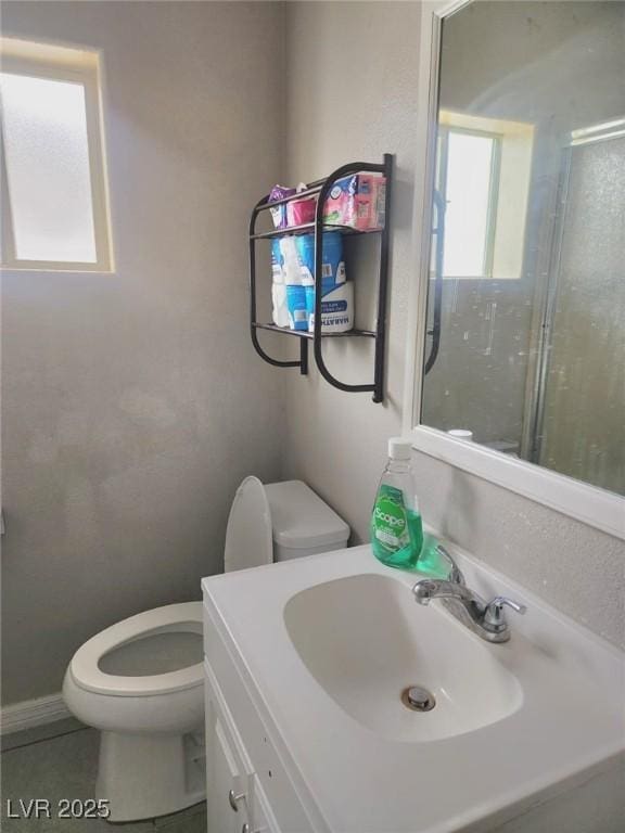 bathroom featuring toilet, tile patterned floors, a shower with door, and vanity