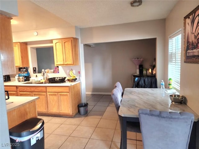 kitchen with light tile patterned floors, light countertops, a textured ceiling, and a sink