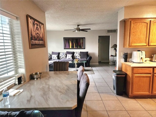 dining space with light tile patterned floors, a textured ceiling, visible vents, and a ceiling fan