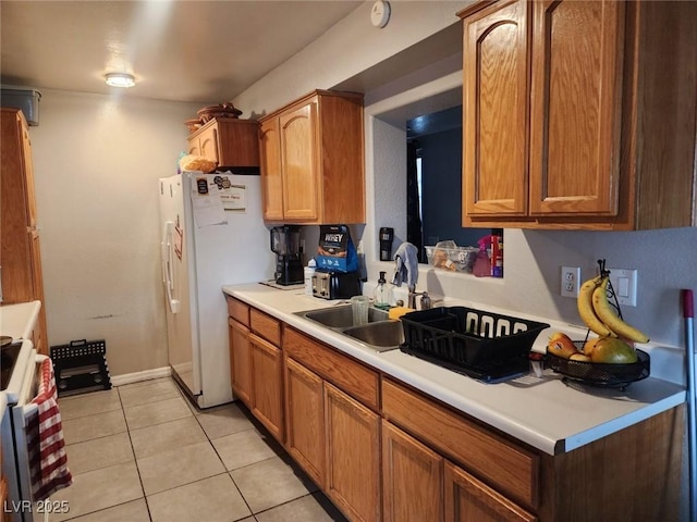 kitchen with white appliances, light tile patterned floors, brown cabinetry, light countertops, and a sink