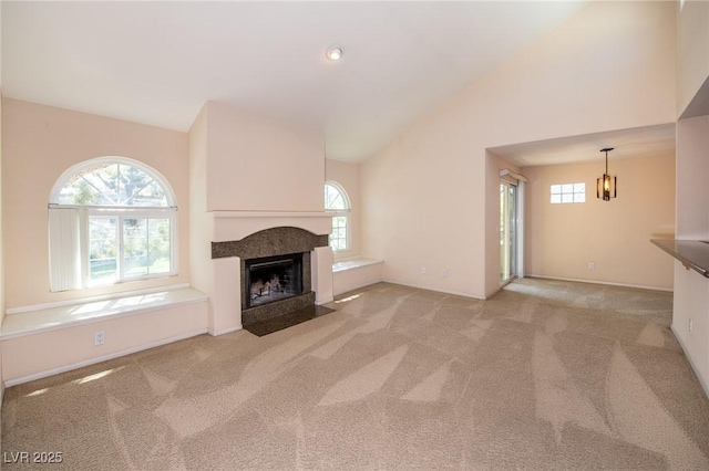 unfurnished living room featuring high vaulted ceiling, carpet, baseboards, and a fireplace with flush hearth