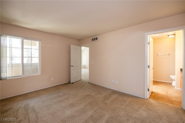 unfurnished bedroom with light carpet, visible vents, baseboards, and ensuite bathroom