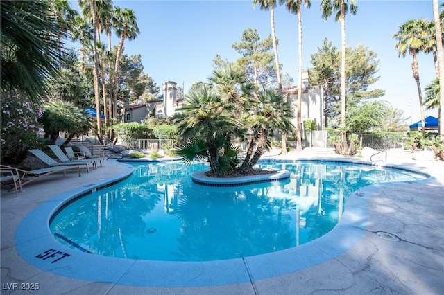 community pool with a patio area and fence