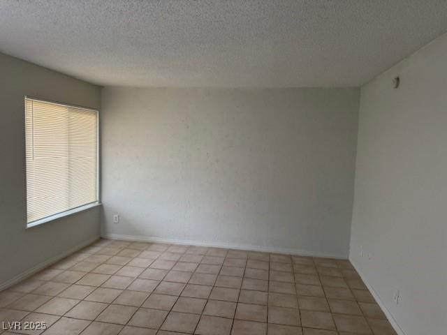 spare room with a textured ceiling and light tile patterned floors