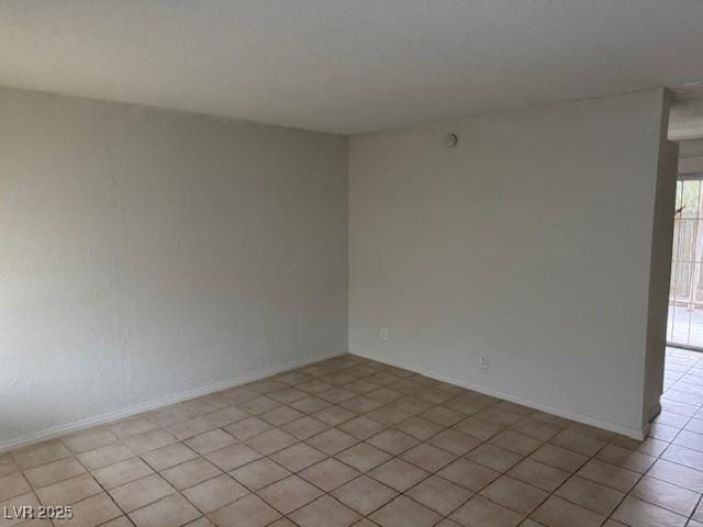 empty room with baseboards and light tile patterned floors