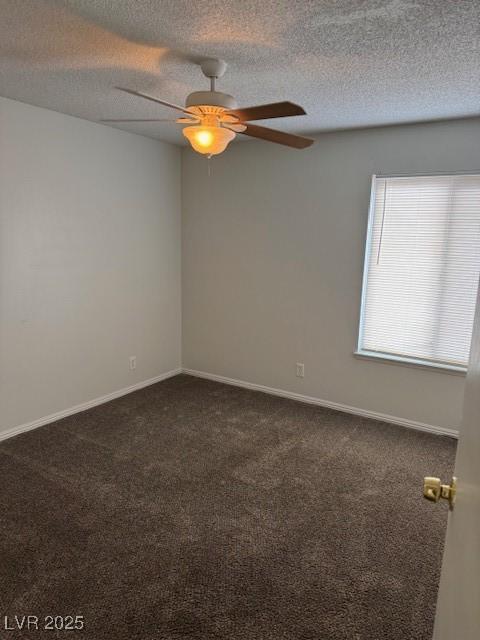 spare room featuring a ceiling fan, dark colored carpet, a textured ceiling, and baseboards