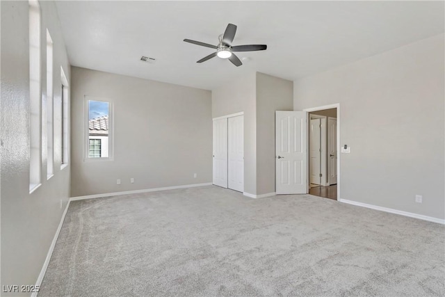 unfurnished bedroom featuring carpet flooring, a ceiling fan, visible vents, baseboards, and a closet