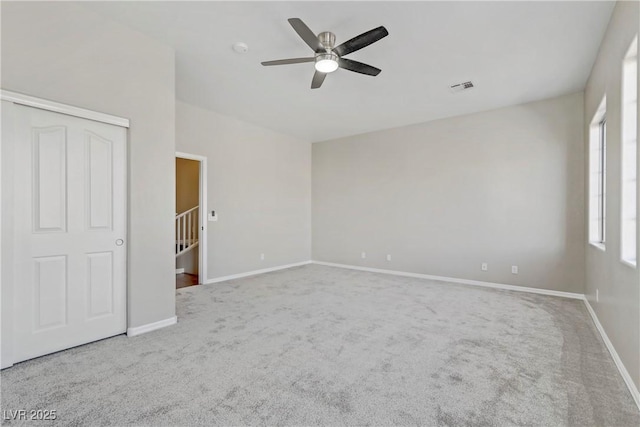 carpeted empty room featuring a ceiling fan, visible vents, and baseboards